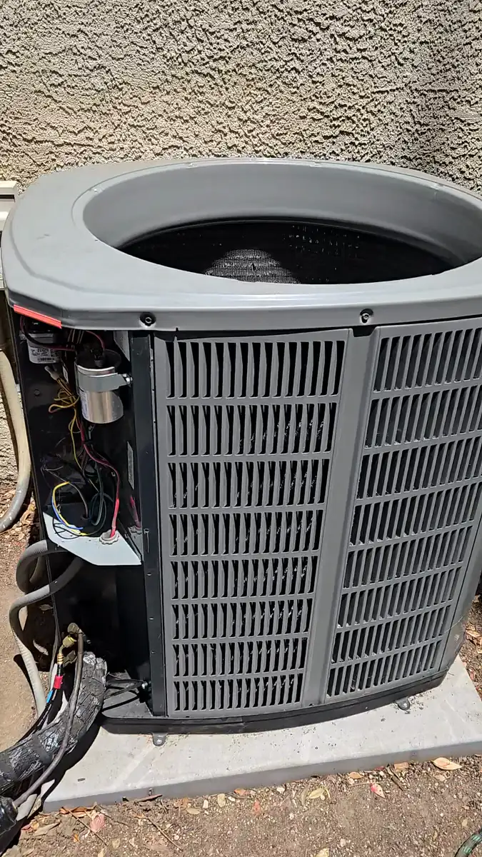The open electrical compartment of the condenser during the repair, showing the run capacitor and wiring