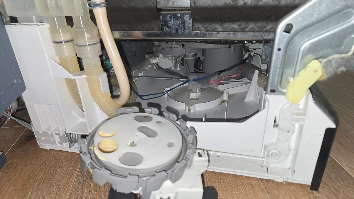 Bosch dishwasher base opened from below, with the round diverter assembly in a gloved hand