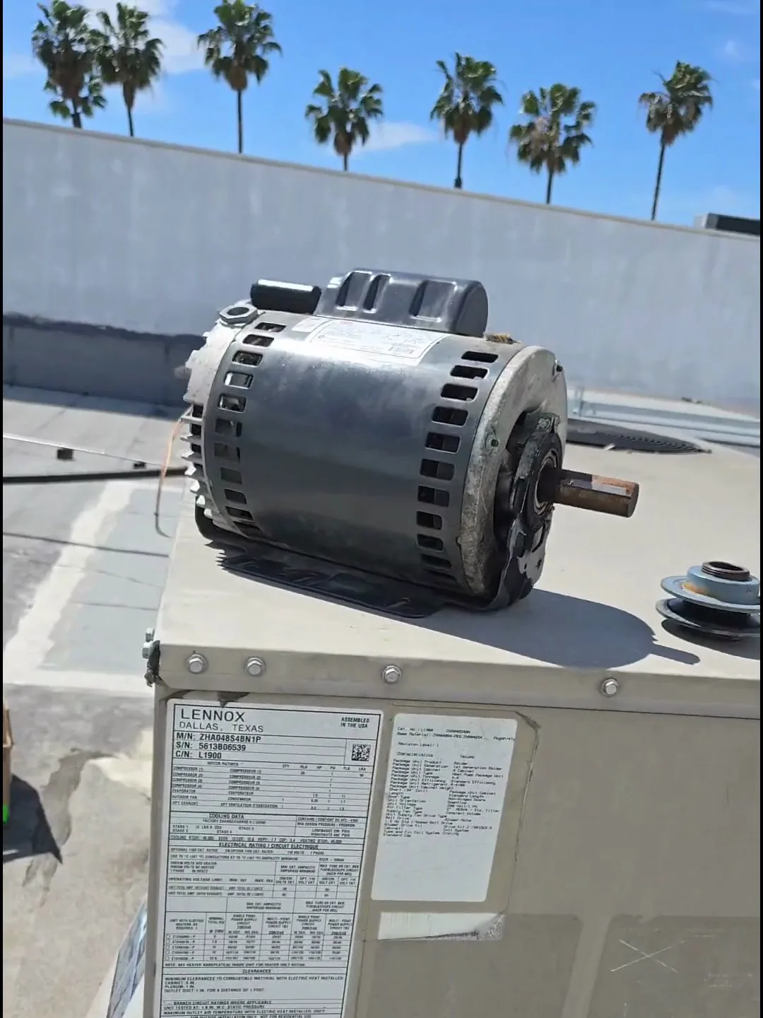 A technician replacing a burned-out blower motor inside a commercial rooftop package unit serving a Los Angeles nail salon.