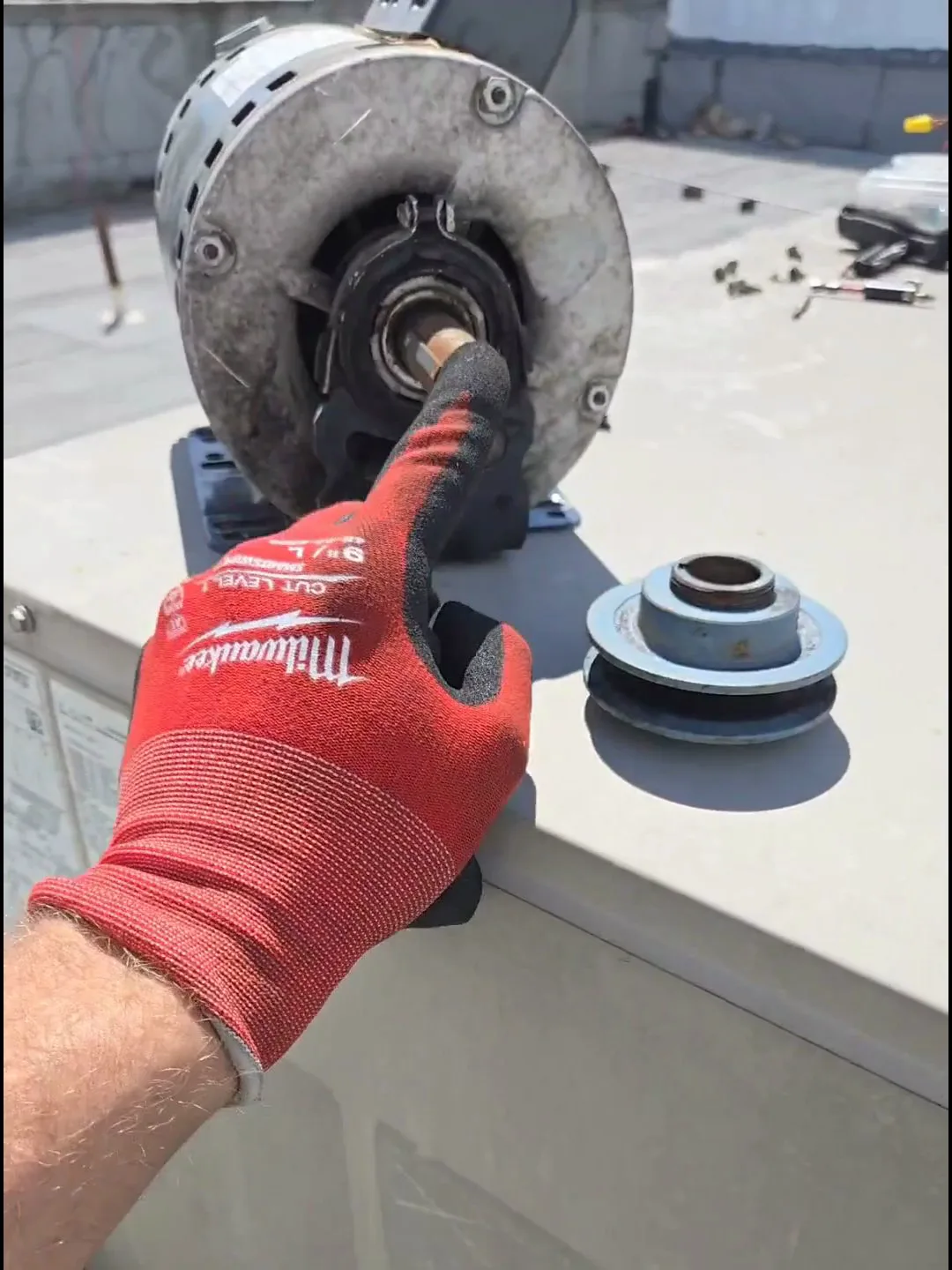 The new motor's 5/8-inch shaft next to the old drive sheave, whose larger bore wouldn't fit it — the mismatch that meant a trip to the supply house.