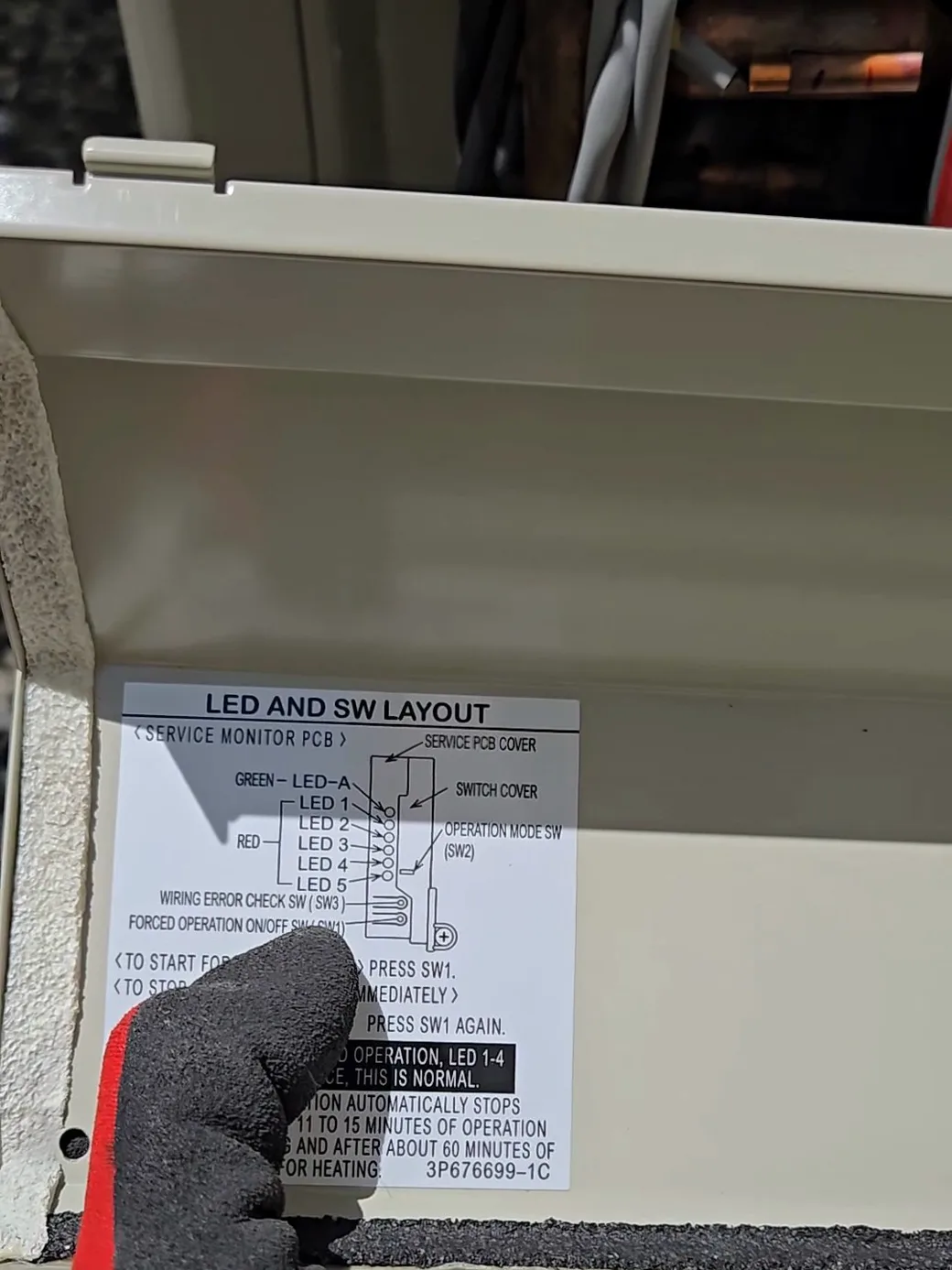 The service label on the outdoor unit board — the connection-check switch that starts Daikin's self-diagnosis.