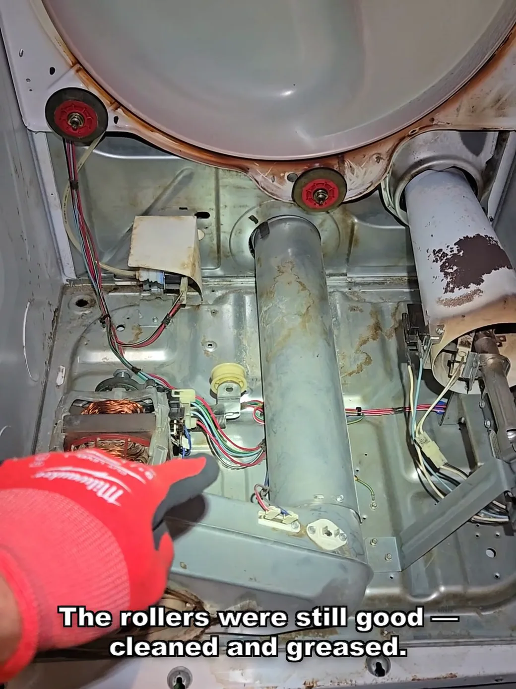 The inside of the dryer cabinet after maintenance — clean base, serviced drum rollers, clean motor, and a clean burner area.