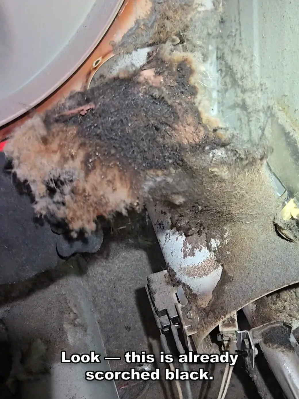 Lint inside the dryer cabinet scorched black around the heat source, showing where a fire had already started to ignite.