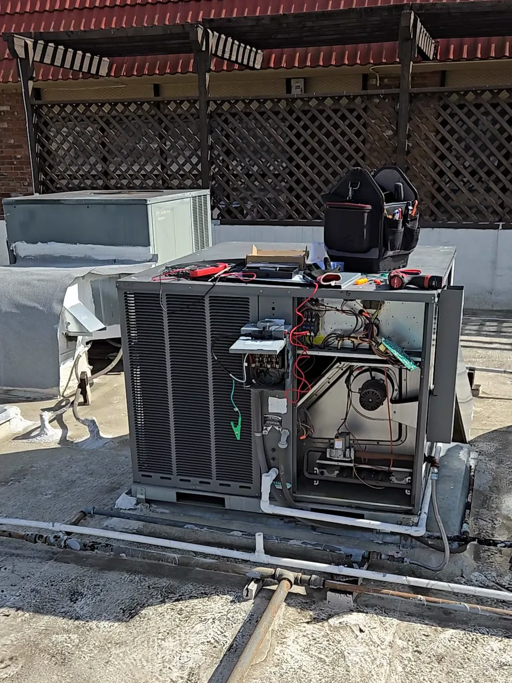 A technician working on a commercial rooftop packaged HVAC unit above a Los Angeles pharmacy.