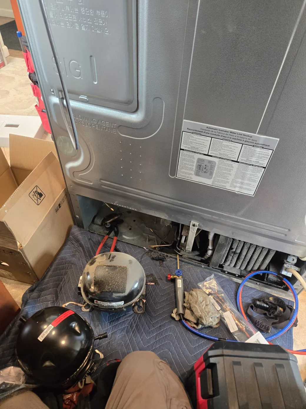 The failed LG linear compressor removed and set on a blanket beside its R134a replacement during the Santa Monica repair.