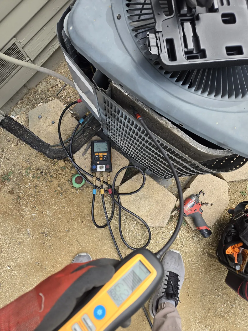 An electronic leak detector and manifold gauges connected to the R22 condenser unit to pinpoint the refrigerant leak in Sherman Oaks.