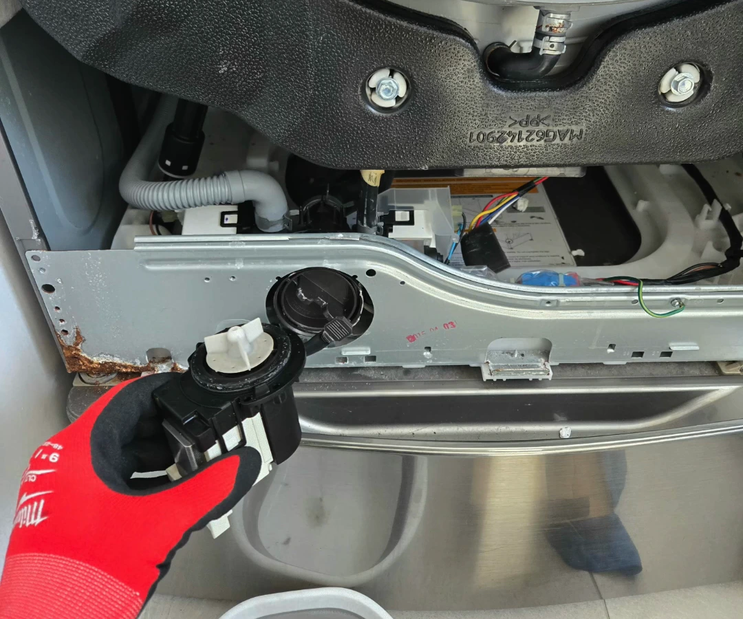 Old LG drain pump held in front of the washer with its replacement installed