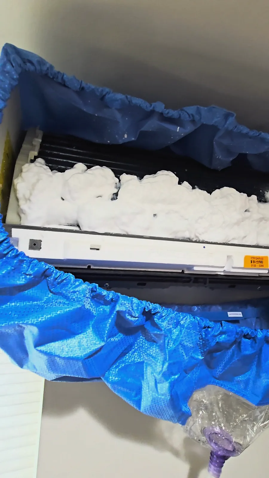 Foaming coil cleaner covering a Daikin mini-split coil, with a cleaning bag hung underneath