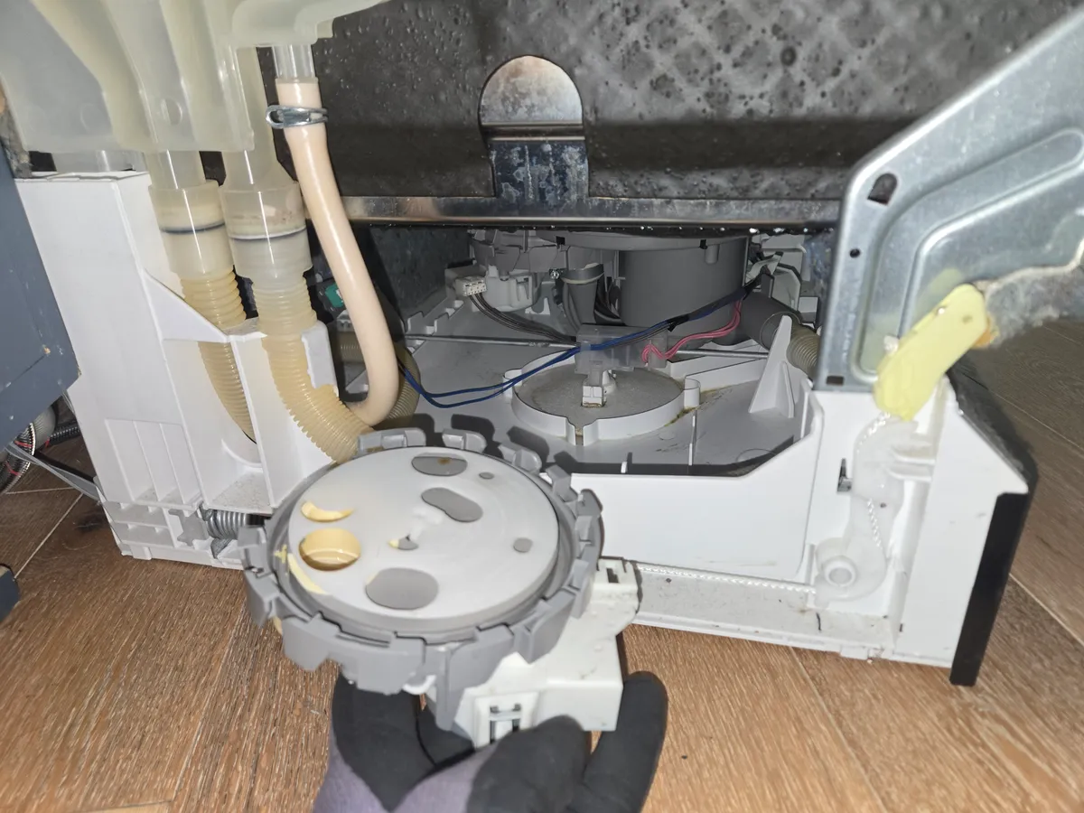 Bosch dishwasher base opened, with the diverter assembly in a gloved hand