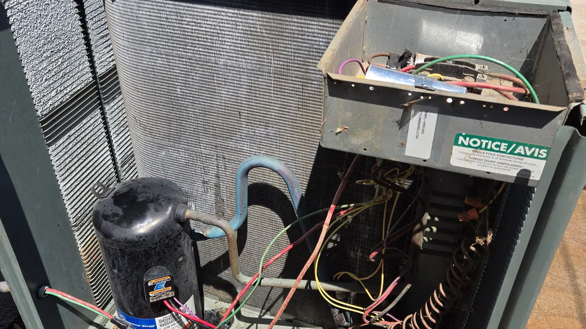 The same AC condenser after a chemical coil cleaning, the coil much lighter, the compressor glossy black and the control box tilted open