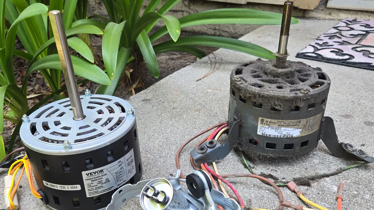 Old blower motor caked in gray dust next to a new replacement motor on a concrete step