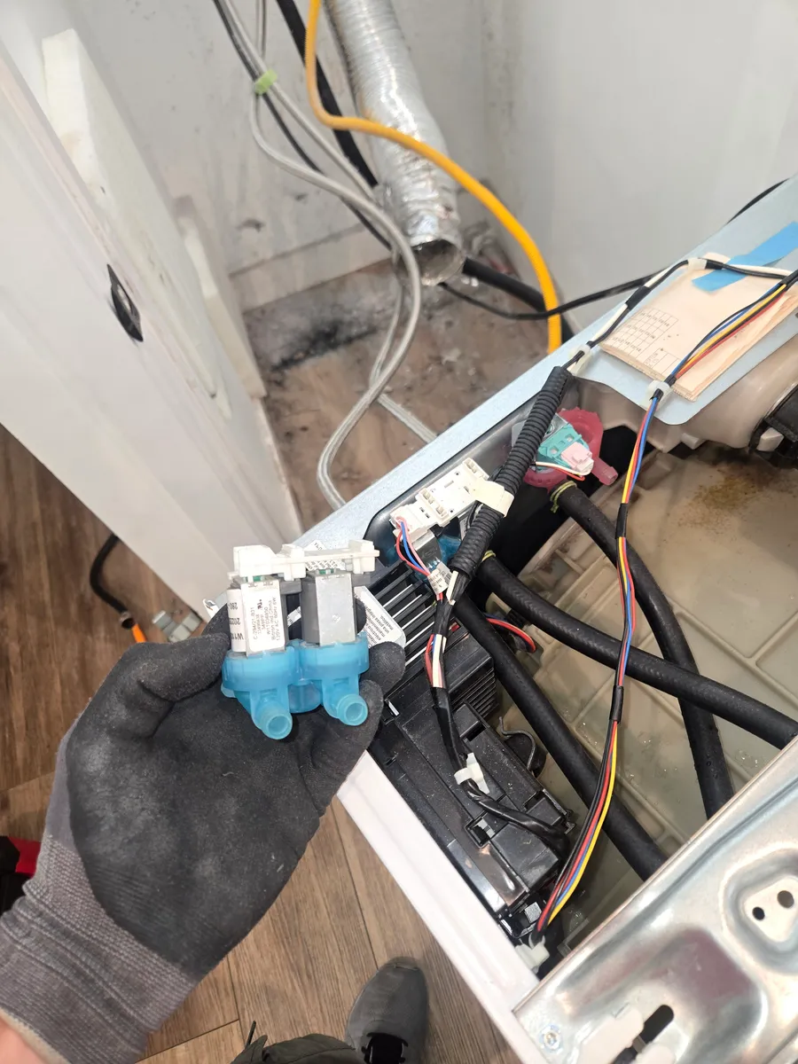 Two-coil water inlet valve held over an opened Maytag washer