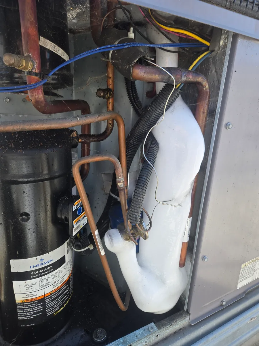 Thick ice on the suction line next to the Copeland scroll compressor inside a packaged AC unit