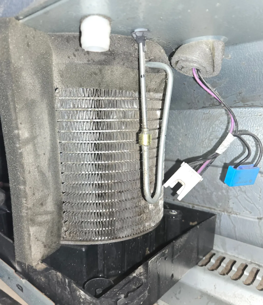 The Samsung refrigerator's condenser coil after cleaning, its rows of thin metal fins clean